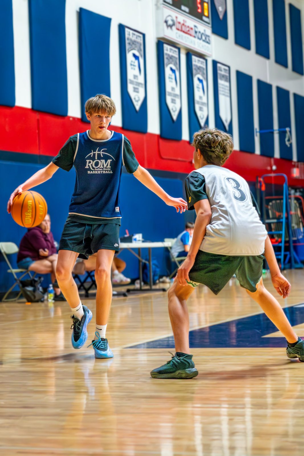Two boys playing basketball in a gymnasium during a game