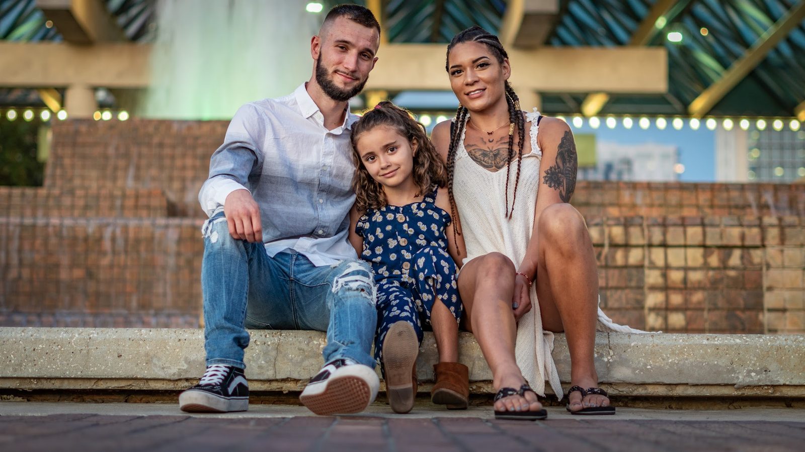 Family of three sitting together on a stone ledge outdoors