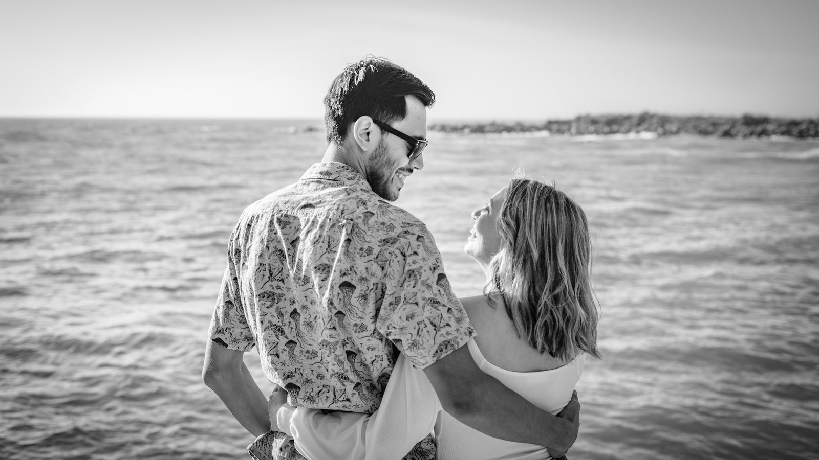Couple embracing by the sea in black and white