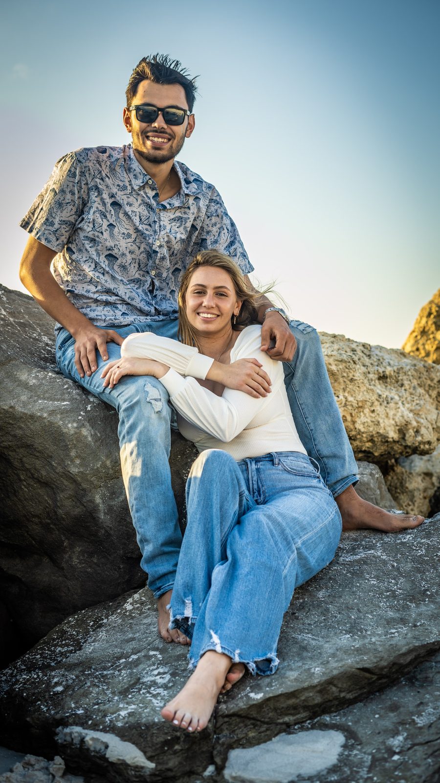Couple sitting on rocks at sunset
