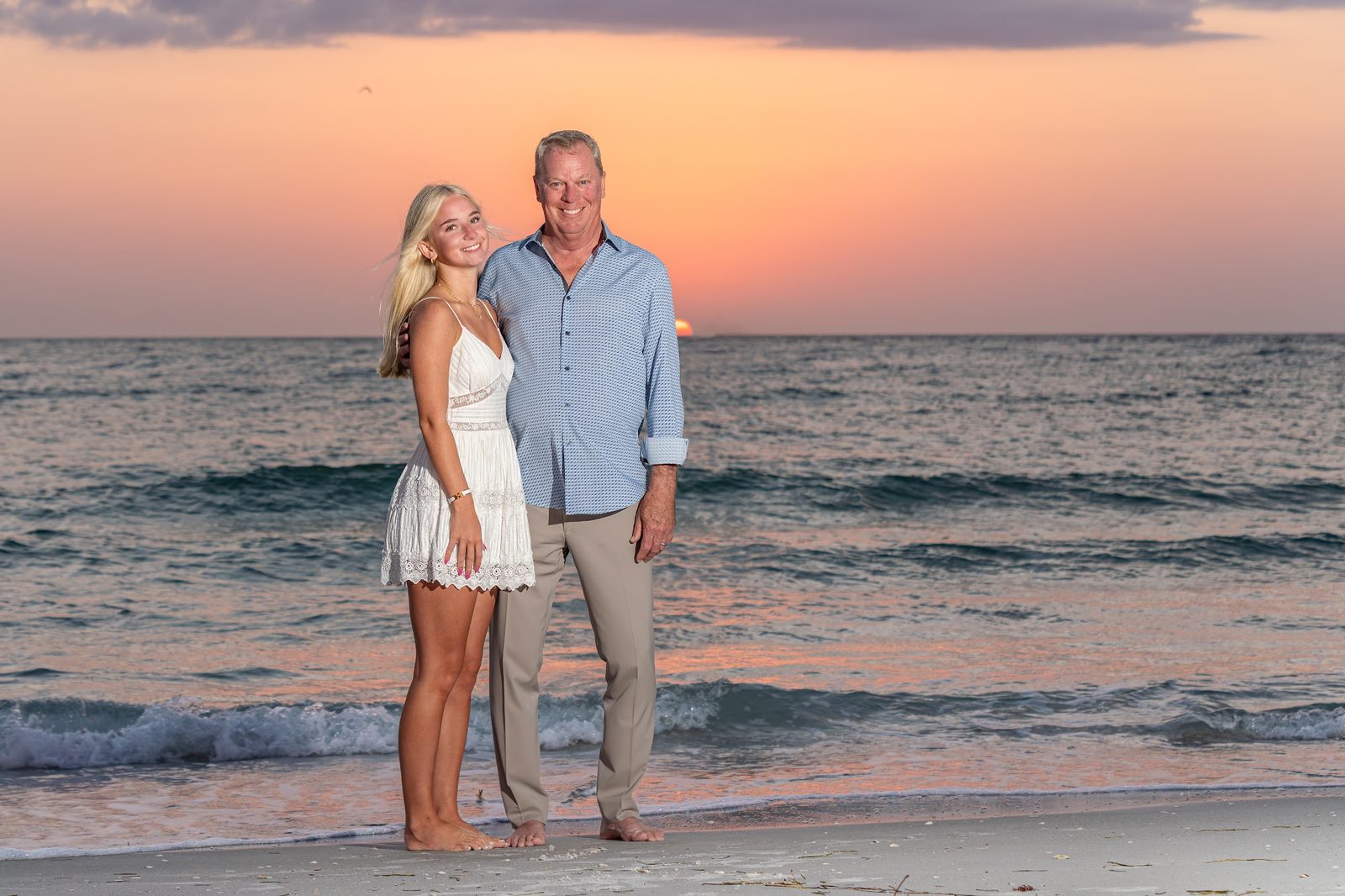Couple posing on beach at sunset with ocean in background