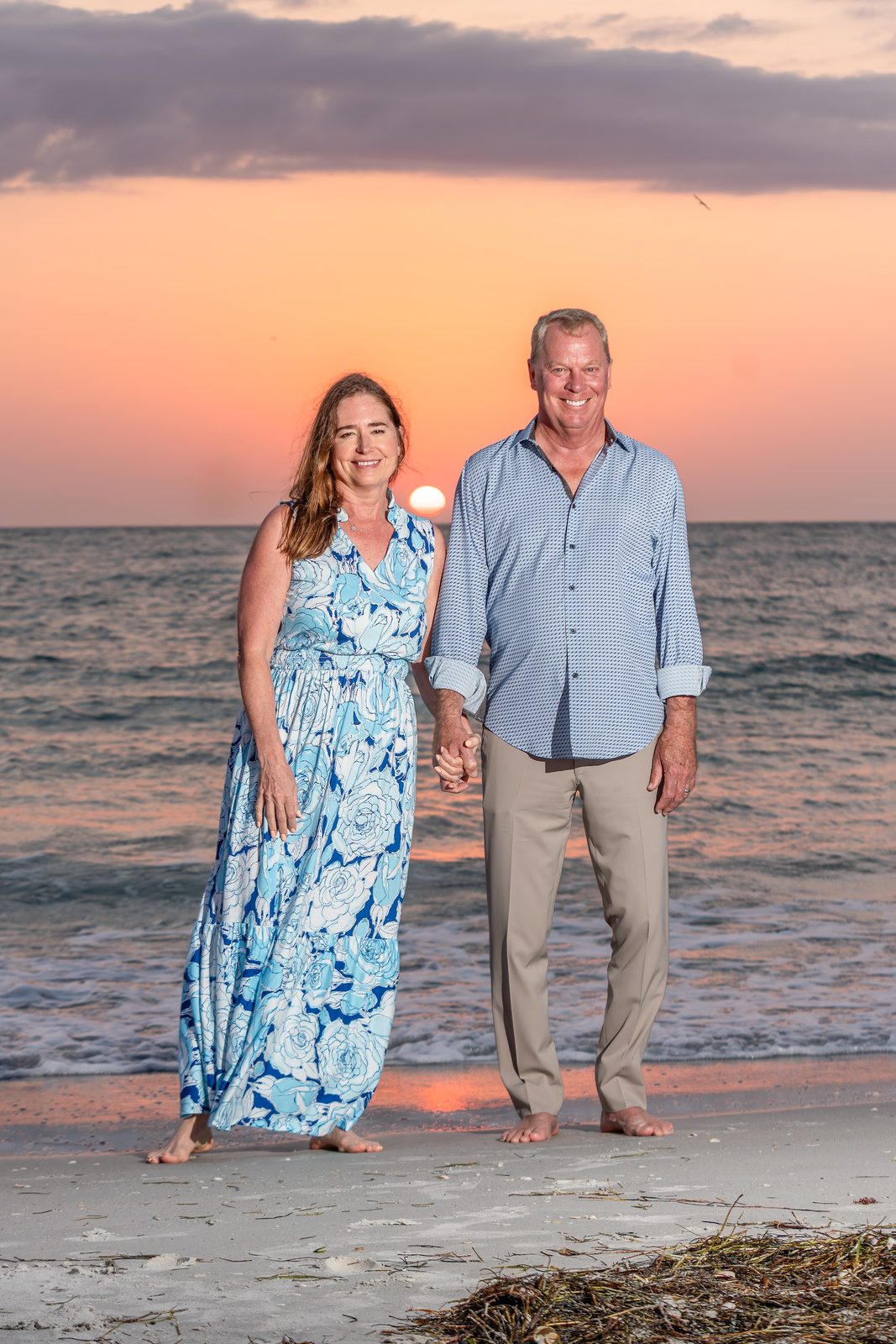 Couple holding hands on beach at sunset