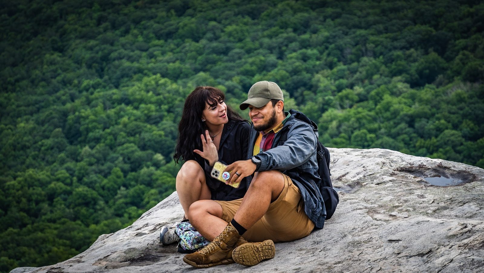Couple sitting on rock overlooking forest
