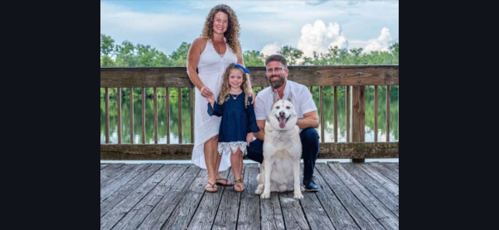 Family group with child and dog on wooden dock by water