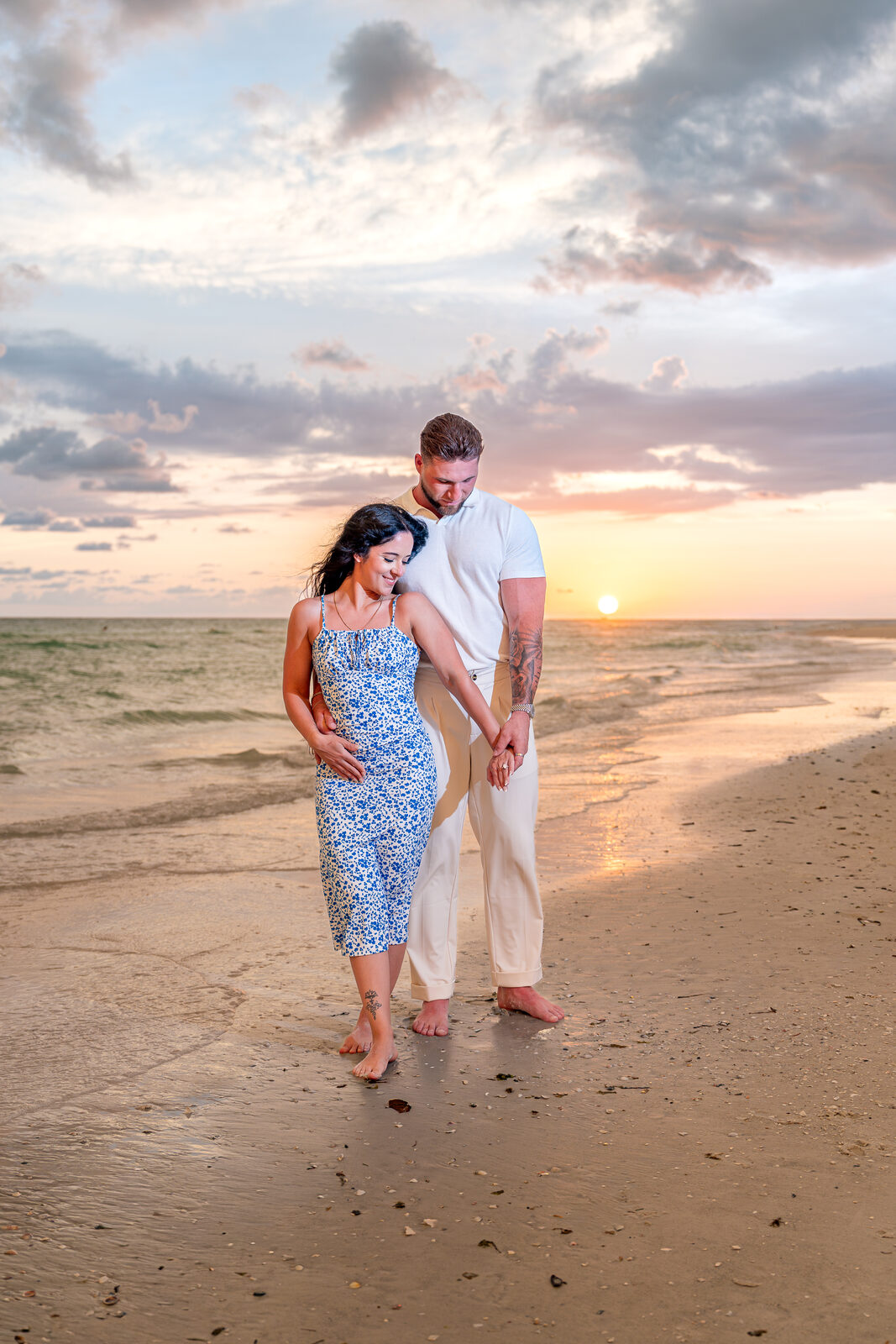 man and woman standing on the beach at sunset