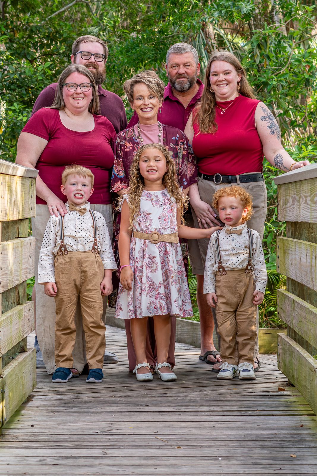 Family group posing on wooden bridge with greenery background