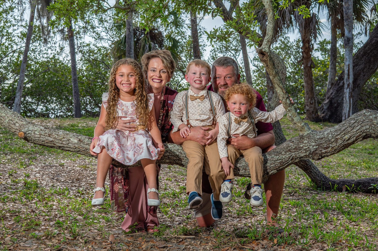 Family group sitting on a tree branch in a park