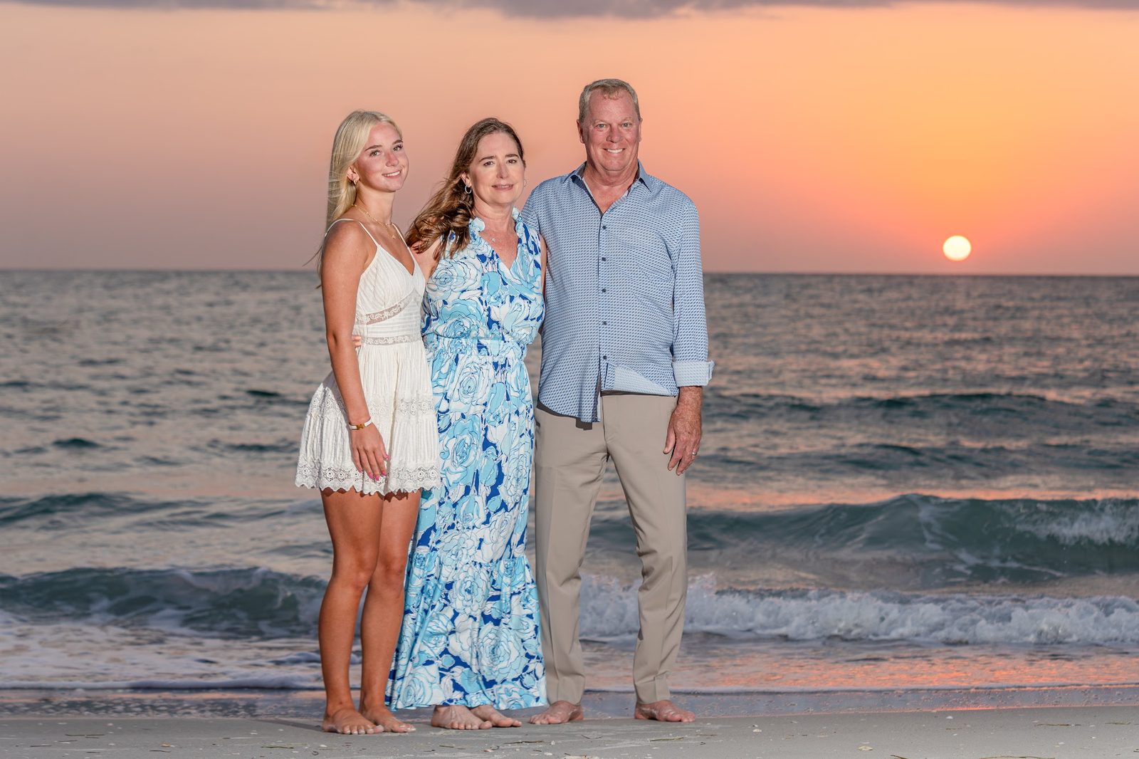 Family posing on beach at sunset with ocean waves