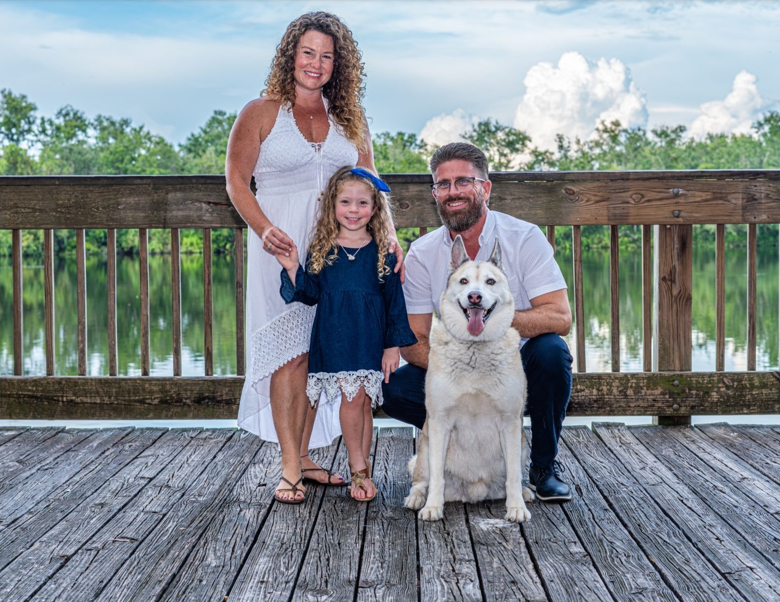Family group with dog on wooden dock by lake