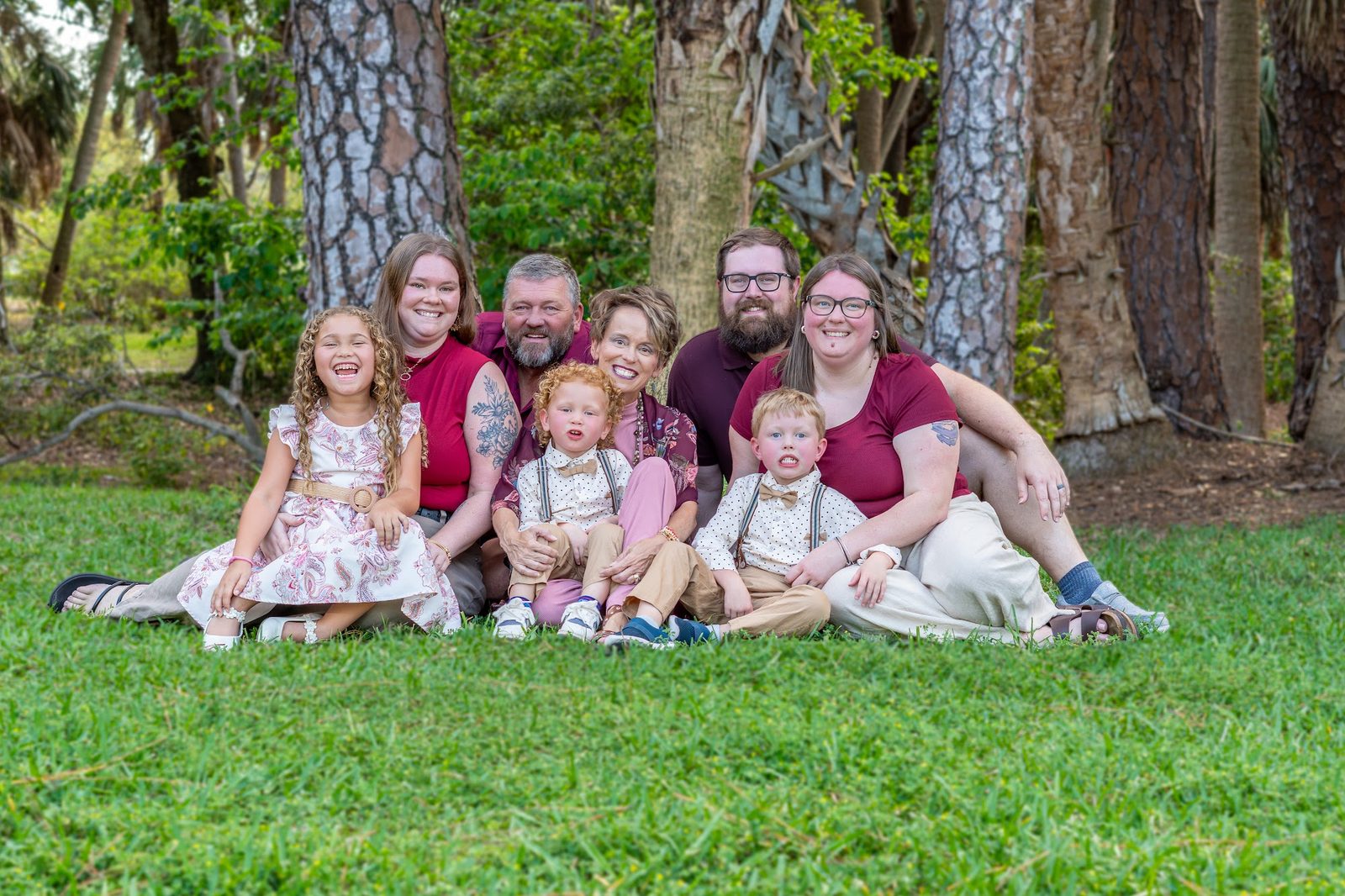 Family group photo on grass with trees in background