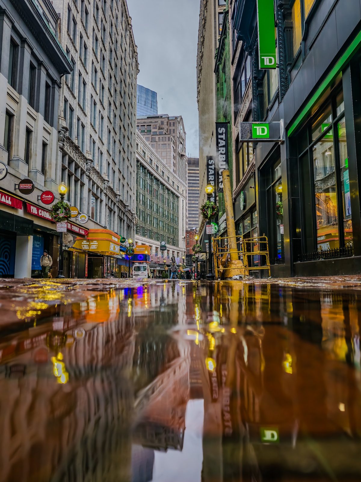 Urban street with wet pavement reflecting buildings and shops