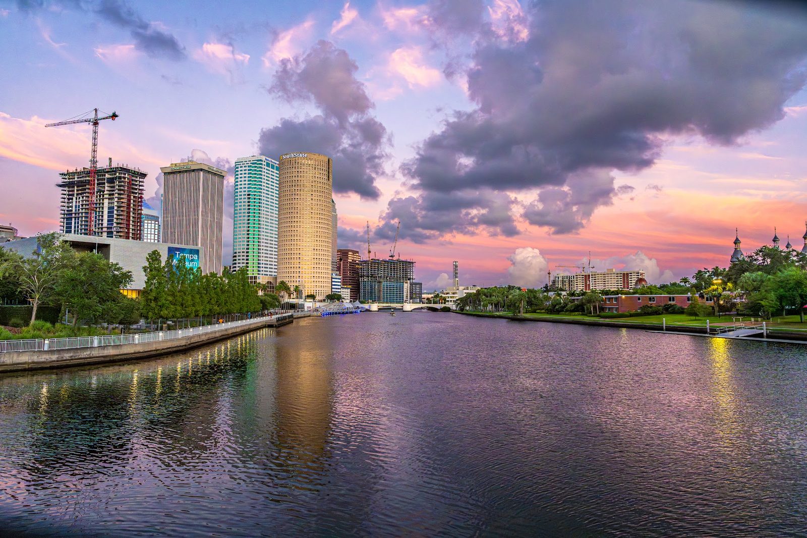 City skyline with river at sunset, buildings and cranes