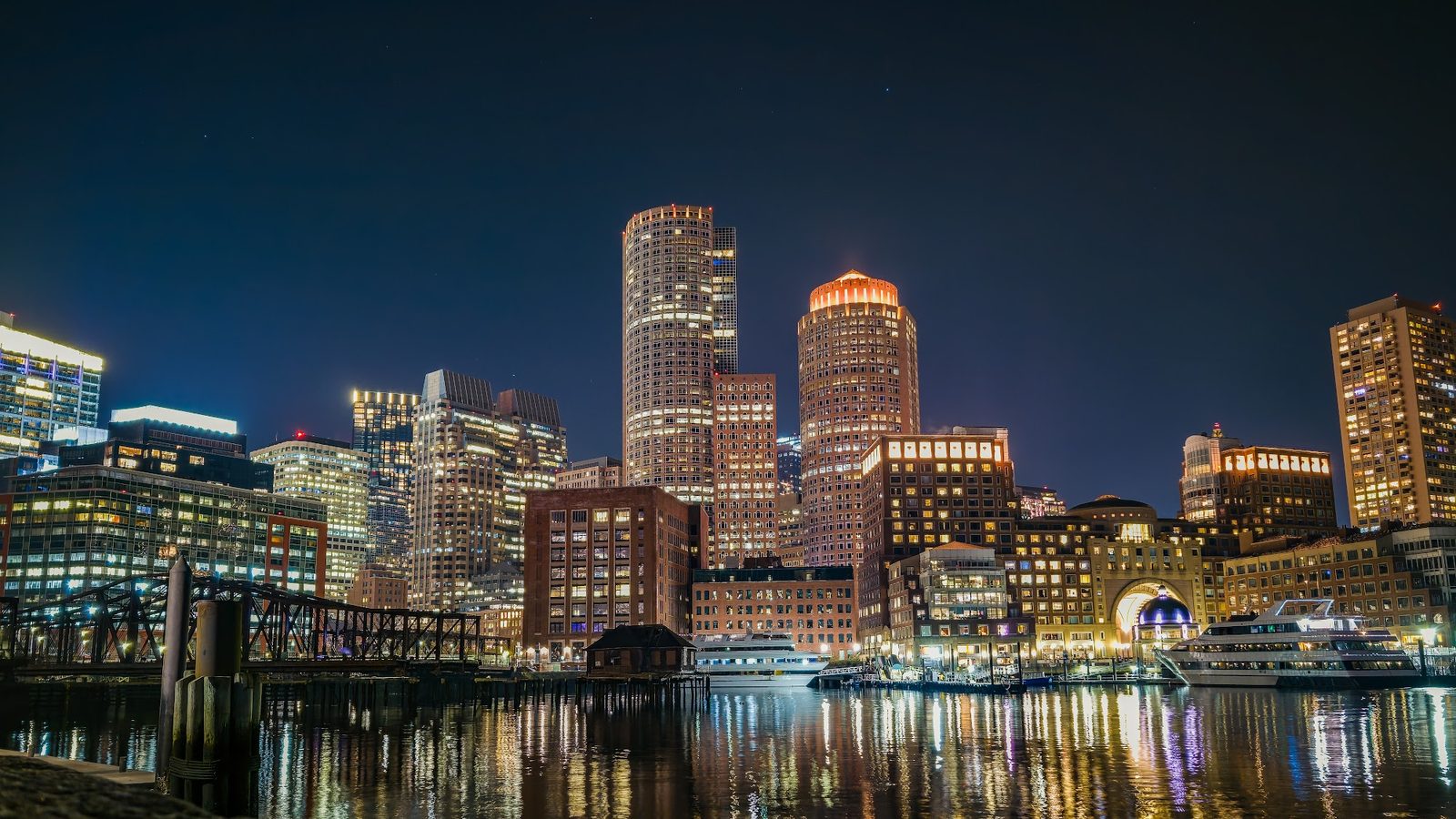 Nighttime city skyline with illuminated buildings and water reflection