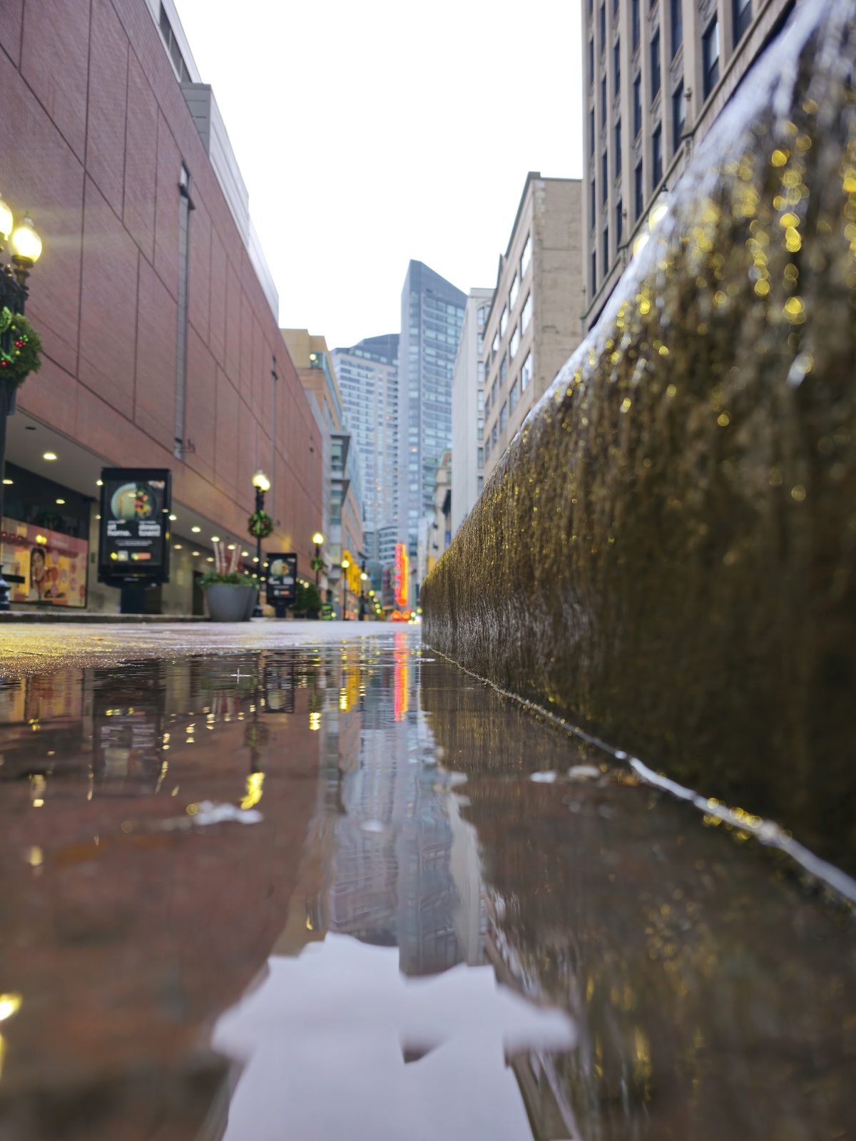 Urban street with wet pavement reflecting buildings and fountain