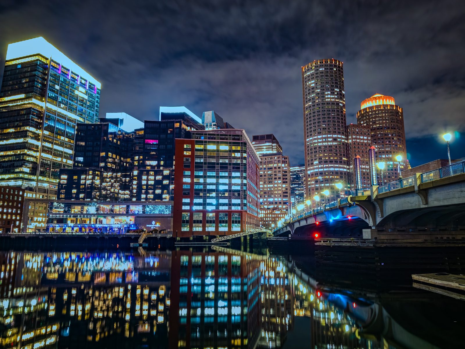 Nighttime city skyline with illuminated buildings and bridge reflections