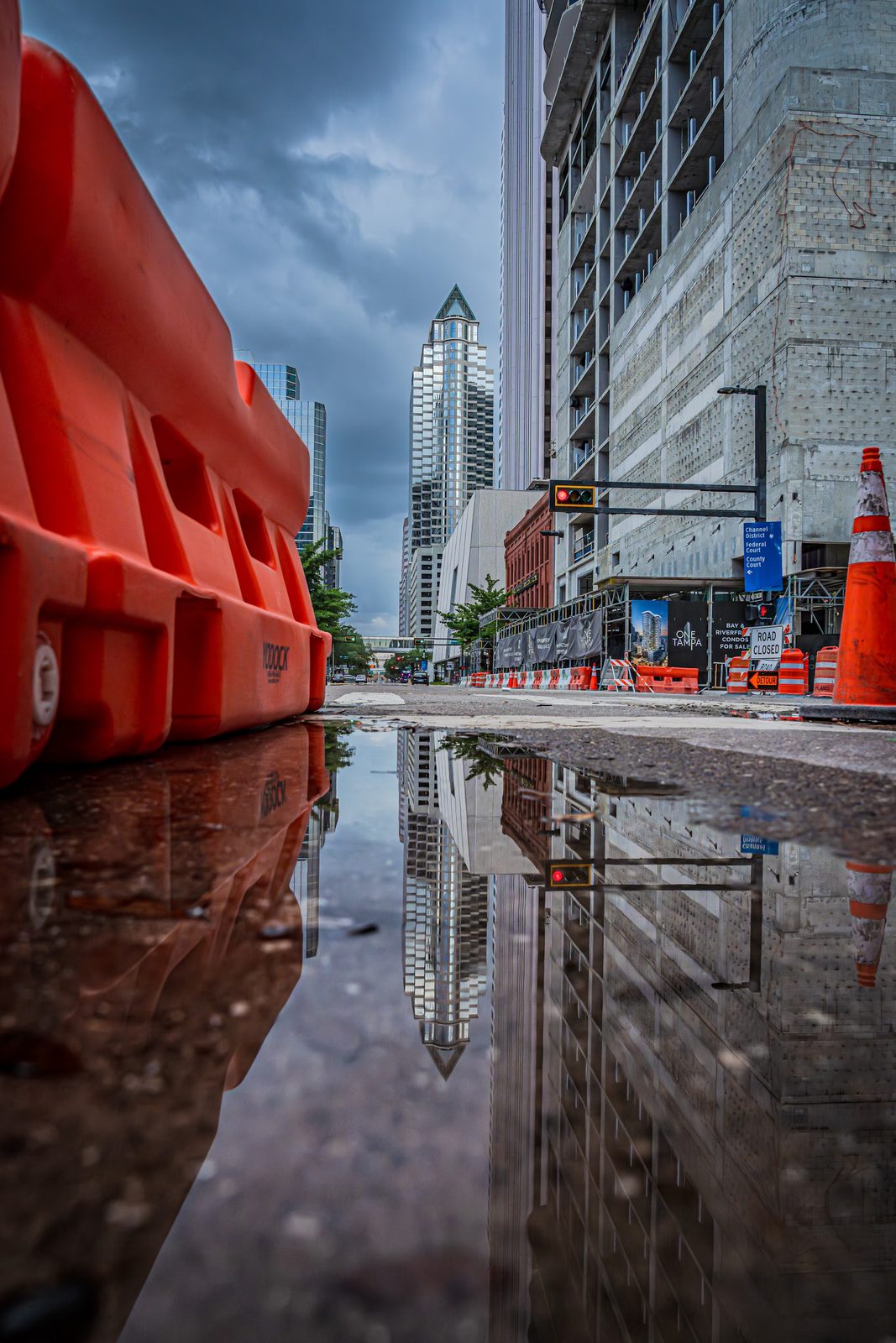 Urban street with construction barriers and puddle reflection