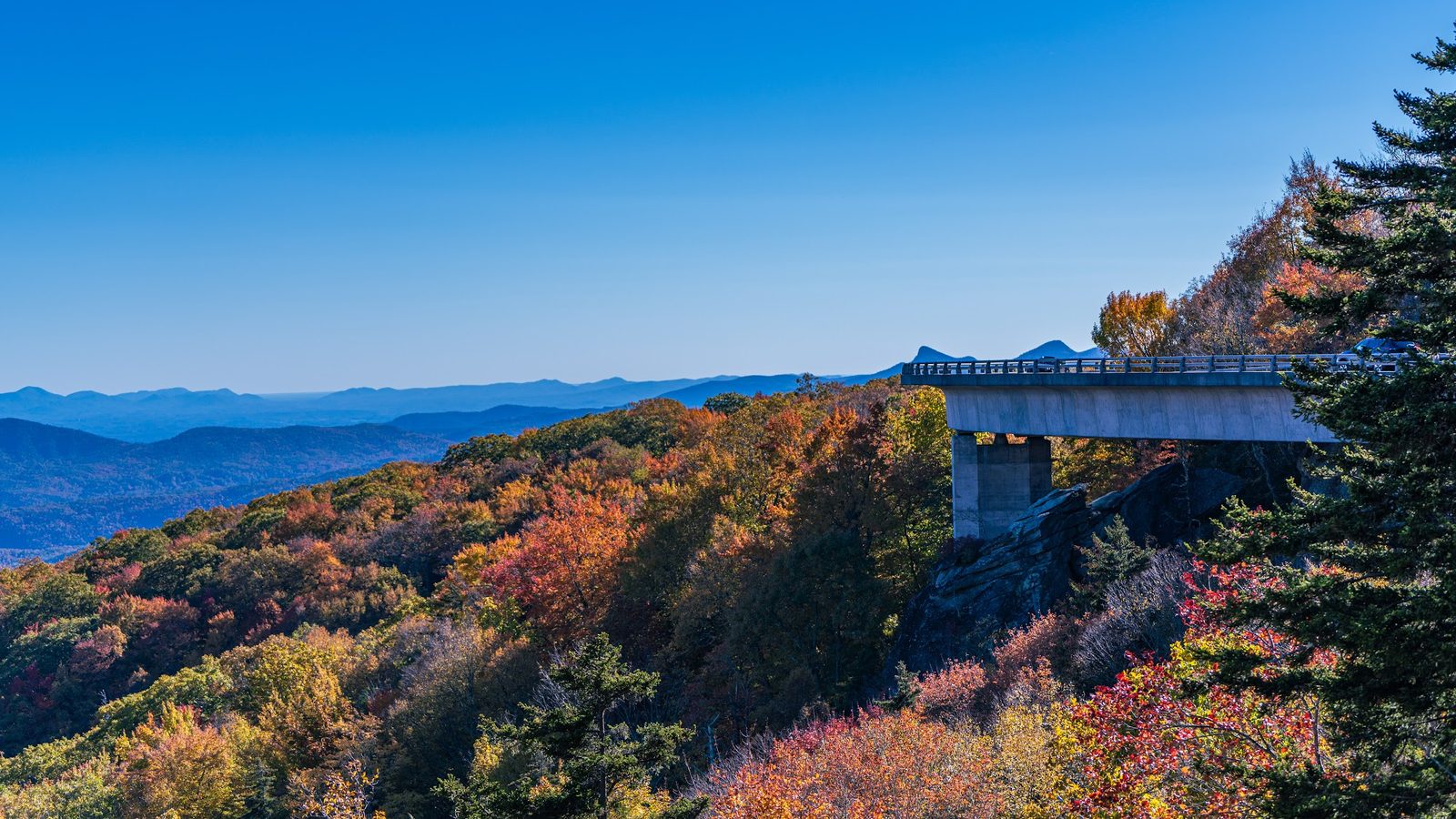 Autumn landscape with bridge over forested mountains
