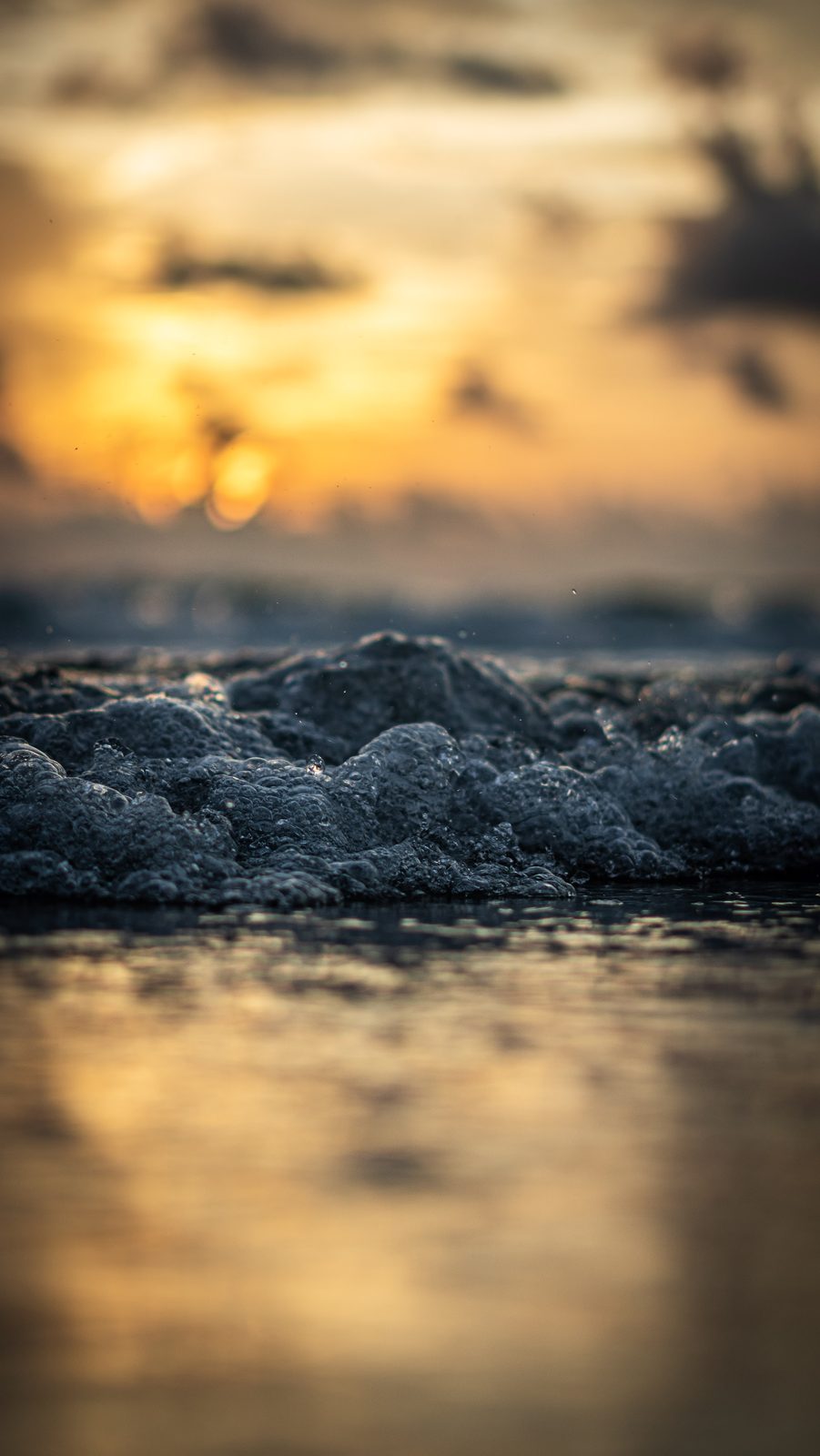 Sunset over ocean waves with foamy surf and golden sky