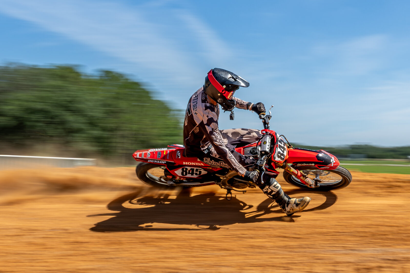 Dirt bike rider kicking up dust on track