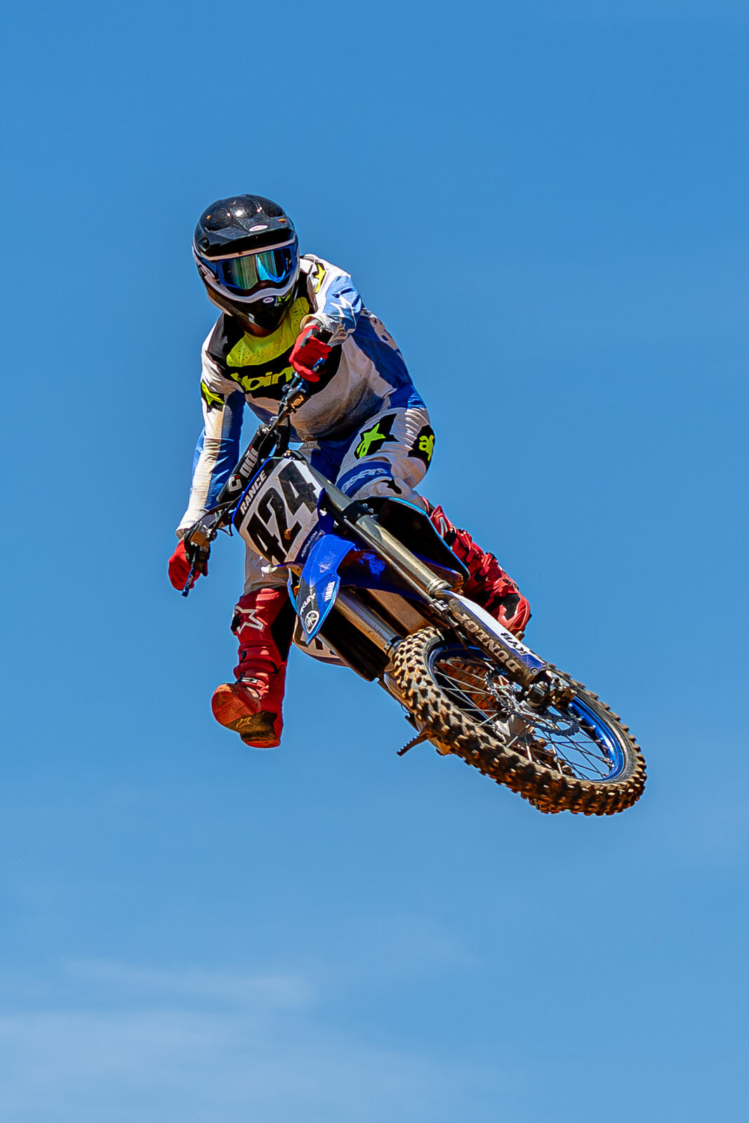 Motocross rider airborne against clear blue sky
