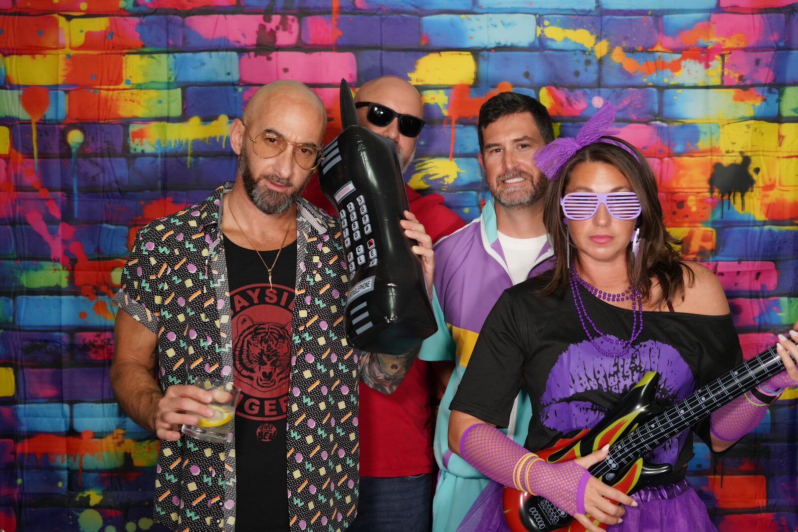 Four people posing with props at a photo booth