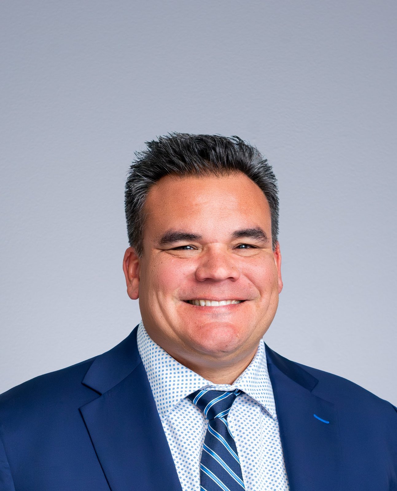 Headshot of a smiling man in blue suit and striped tie
