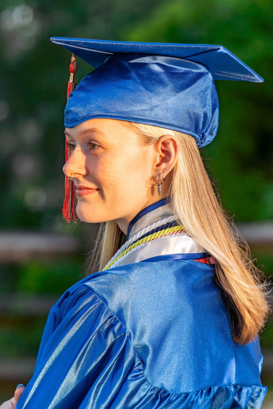 Graduate in blue cap and gown with long blonde hair