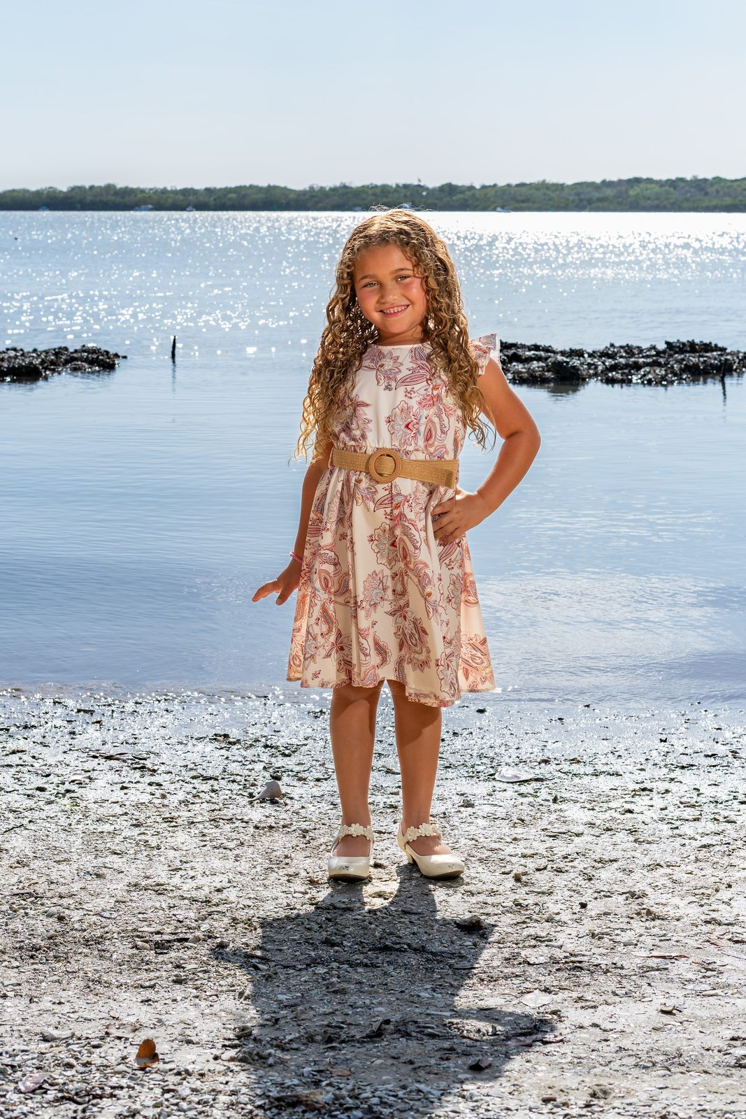 Girl in floral dress posing on beach shore