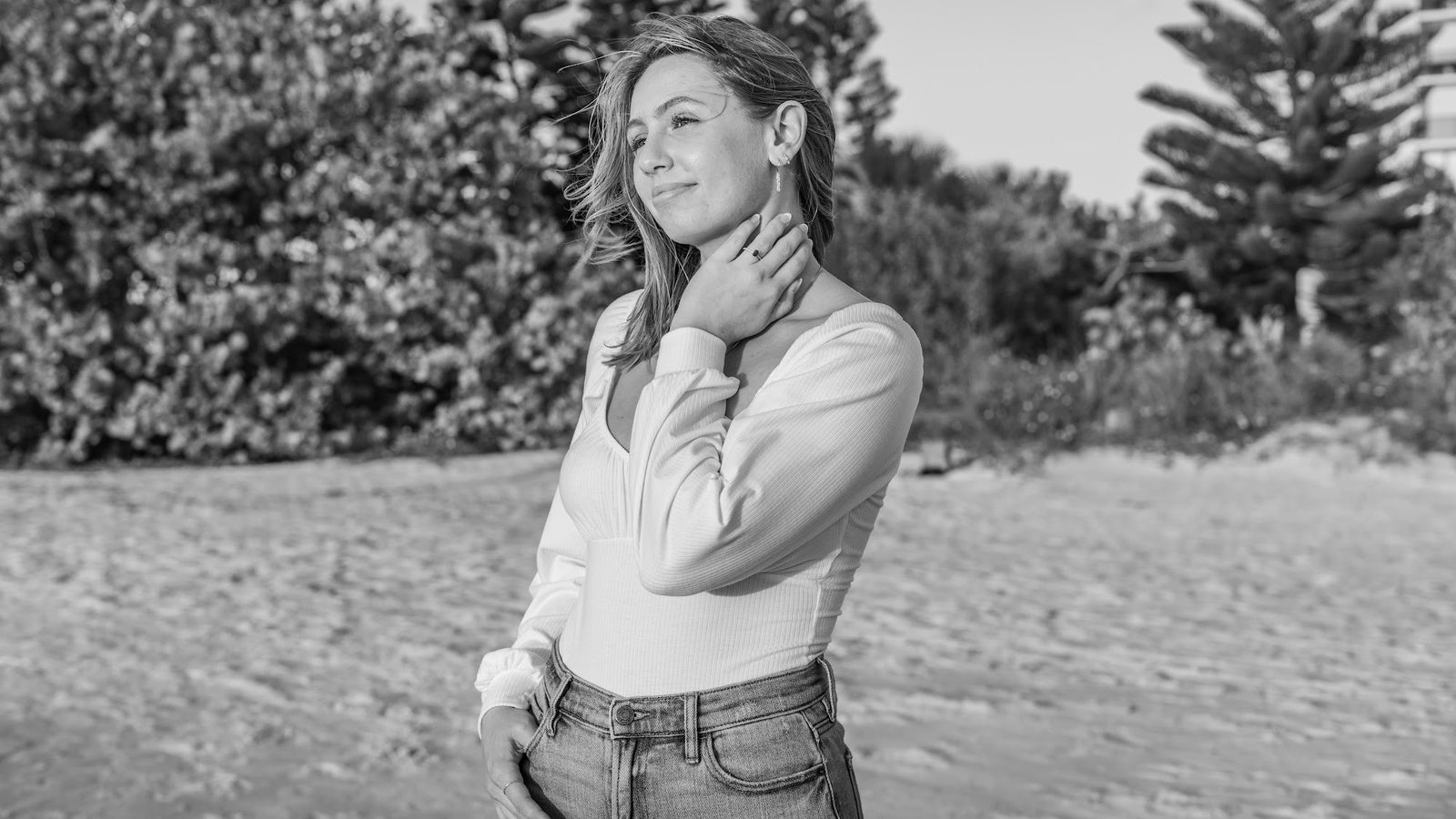 Woman posing outdoors in white top and jeans, black and white portrait