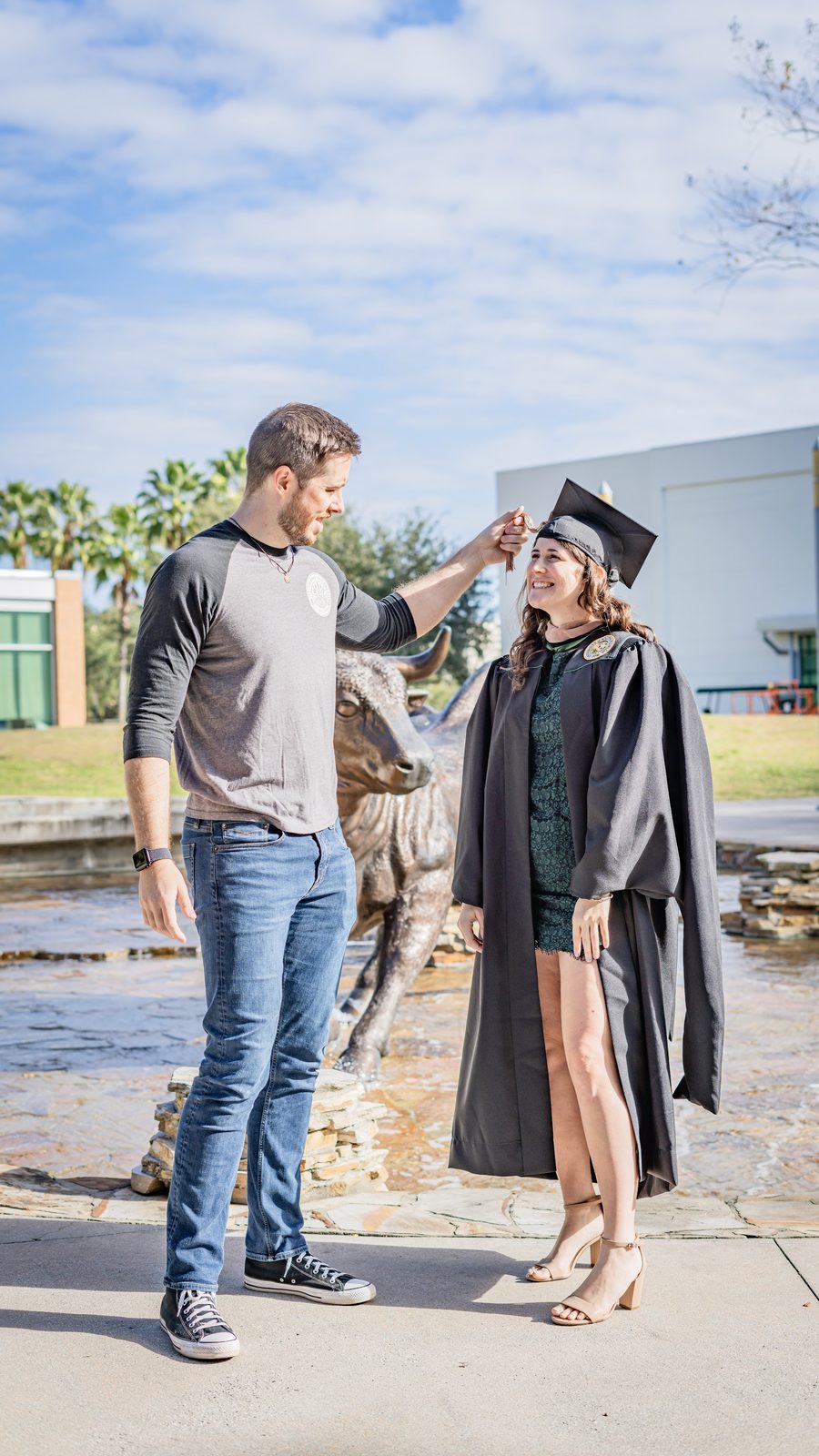 Graduation photo with cap adjustment outdoors near statue