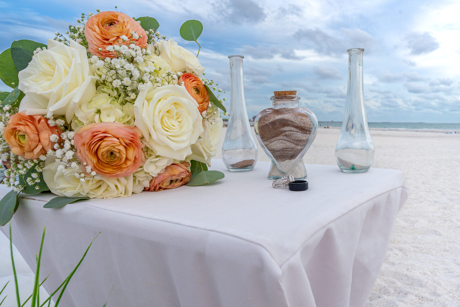 Beach wedding table with bouquet and sand bottles