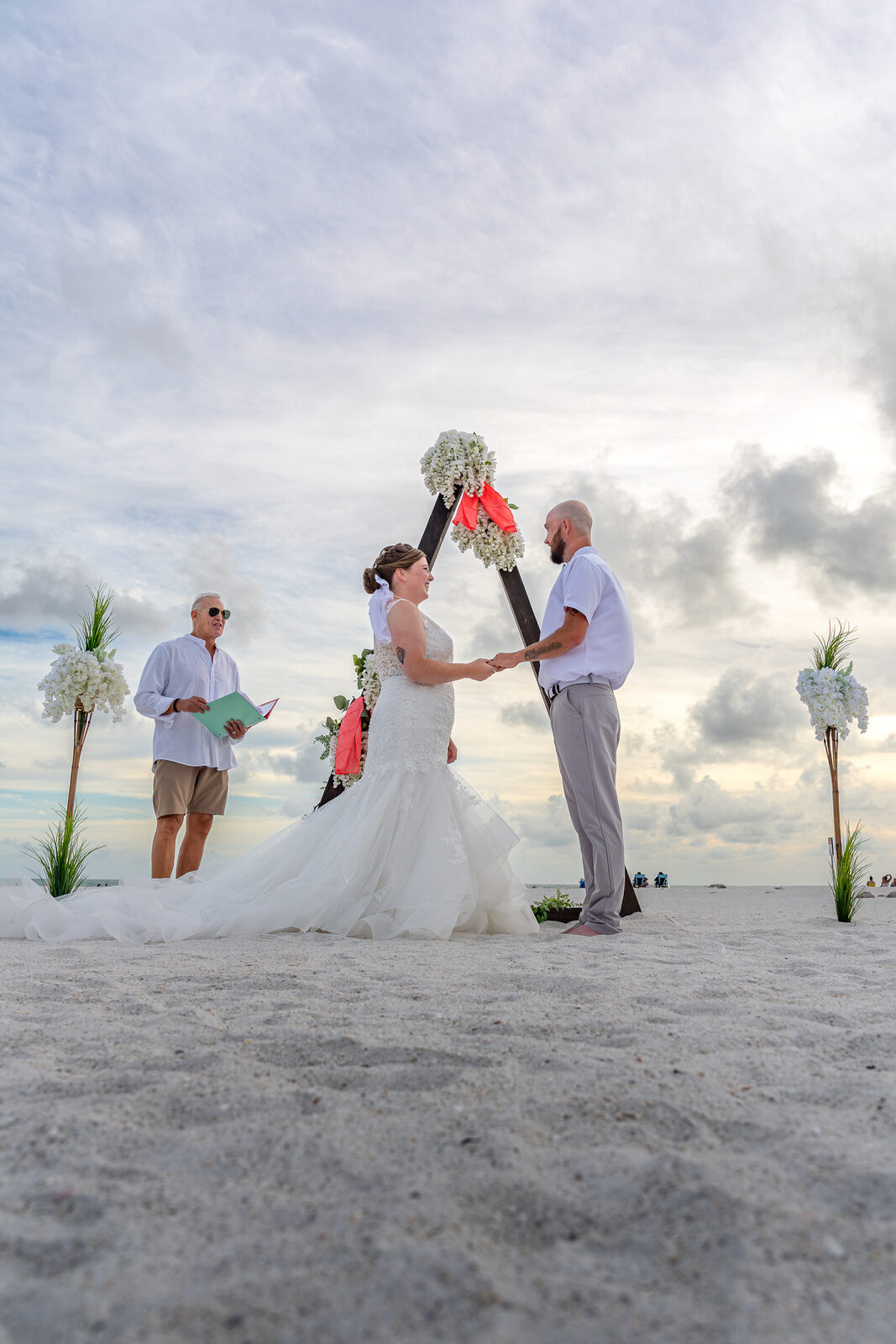 Bride and groom exchanging vows on sandy beach